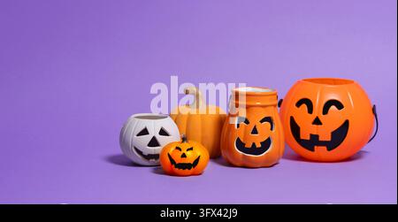 Front view of group of four assorted pumpkins—made of orange ceramic, white ceramic, and orange plastic—featuring black faces with various expressions Stock Photo