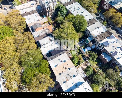 An overhead oblique view follows a tree lined street between two rows of flat roofed buildings. The elevated view of Brooklyn Stock Photo