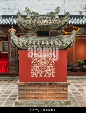 Traditional stone incense burner with intricate dragon art on a red base at Quan Thanh Temple in Hanoi, Vietnam Stock Photo