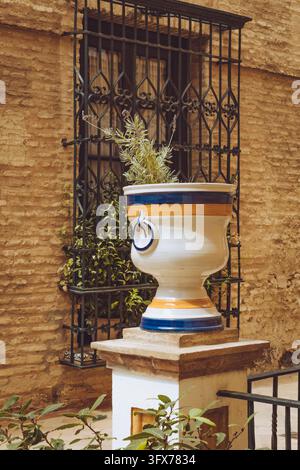 Traditional Andalusian courtyard with a decorated ceramic urn and iron window grate in Seville, Spain. Stock Photo