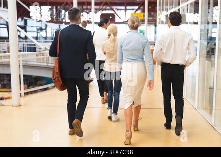 Rear view of diverse business people walking together in the corridor at office. International diverse corporate business partnership concept Stock Photo