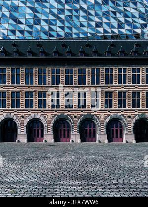 Close up abstract view showing the futuristic glass structure rising above the historic brick fire station at Antwerp Port House. Stock Photo