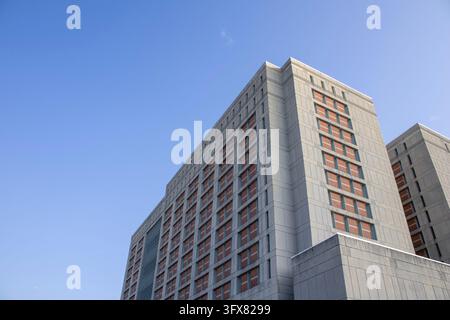 Brooklyn, New York, USA – September 4, 2023: Two pale concrete towers of MDC Brooklyn with narrow windows set against a wide clear blue sky. Stock Photo