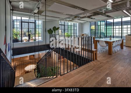 Interior of IDEO's London design studio in Clerkenwell, featuring an open-plan workspace, timber flooring, exposed services and a steel staircase. Stock Photo