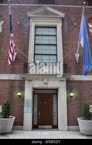 Manhattan, NYC – Dec 24, 2023: Brick NYPD building entrance with a wooden door, planters, and American and New York City flags in Lower Manhattan. Stock Photo