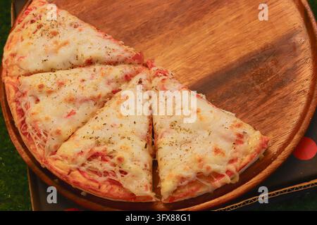 Four fusion pizza slices topped with imitation crab, ham, melted cheese and oregano on a wooden serving board in Bangkok, Thailand. Stock Photo