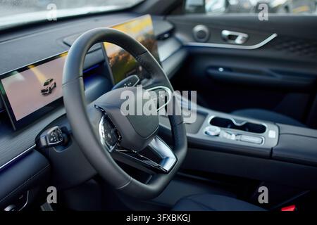 modern and luxurious car interior featuring a sleek steering wheel and dashboard, captured from the passenger seat perspective, highlighting the high- Stock Photo