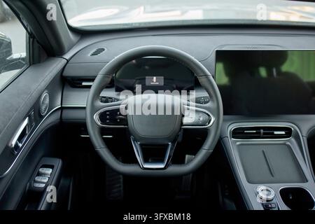 modern and luxurious car interior featuring a sleek steering wheel and dashboard, captured from the passenger seat perspective, highlighting the high- Stock Photo