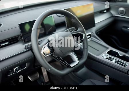 modern and luxurious car interior featuring a sleek steering wheel and dashboard, captured from the passenger seat perspective, highlighting the high- Stock Photo