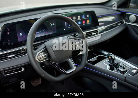 modern and luxurious car interior featuring a sleek steering wheel and dashboard, captured from the passenger seat perspective, highlighting the high- Stock Photo