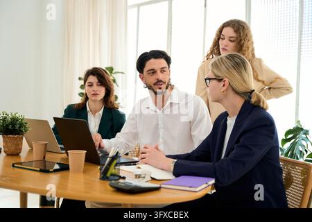 Diverse team of professionals collaborating, discussing project strategies, and working together in a modern office environment Stock Photo