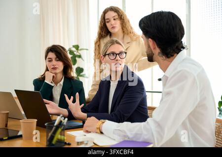 Business team collaborating and discussing strategy during a professional meeting in a modern office setup, focusing on teamwork Stock Photo