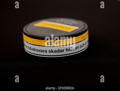 Close-up of a Swedish nicotine pouch can featuring a mandatory health warning label. Studio photograph on a black background with shallow depth of fie Stock Photo