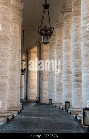 An architectural composition looking down the long covered corridor of berninis massive stone columns located in vatican city, rome, italy Stock Photo