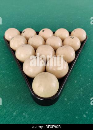 Billiard balls arranged in triangle rack on green felt table for game. Standard set of numbered balls in plastic triangle used for Russian billiards, Stock Photo