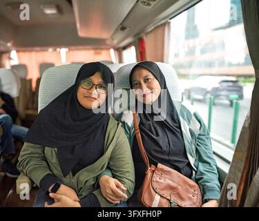 Hijab mother and daughter is sitting in the bus, family travel t Stock Photo