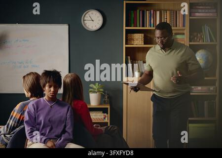 Black Male Therapist Talking to Diverse Teenagers during Group Therapy Stock Photo