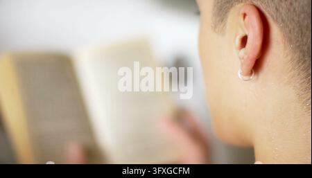 Close-up of a student reading a book at home, with copy space. Focus on learning and education, the image captures a moment of quiet study. Stock Photo