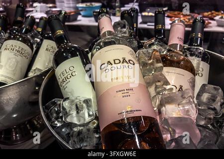 Wine bottles chill in ice buckets, among them a Castelo Rodrigo and a Cadão Douro DOC Rosé 2025. A buffet stands in the background. Barca d'Alva, Figueira de Castelo Rodrigo, Guarda District, Portugal. Stock Photo