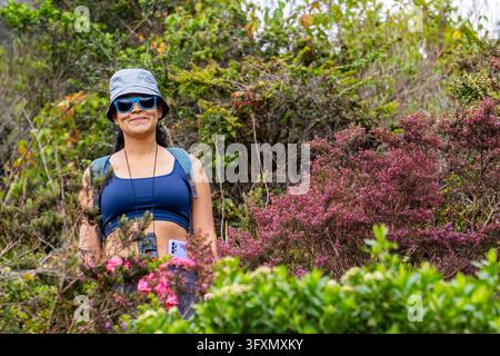 Happy young woman hiker wearing hat and sunglasses standing in mountain nature during trek, active lifestyle. High quality photo Stock Photo