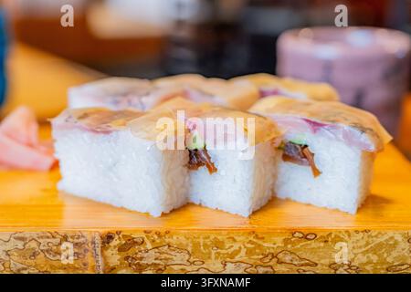 Tokyo, Japan, NOV 22, 2024 - Several pieces of sushi rolls topped with fish and thin egg crepe are arranged on a wooden board with pickled ginger on t Stock Photo