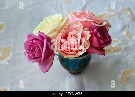 Delicate small bouquet of beautiful colorful roses on white drapery Stock Photo
