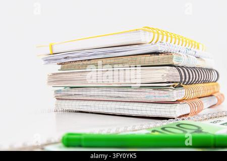 Stack of spiral notebooks with euro banknotes and a green pen on a desk Stock Photo