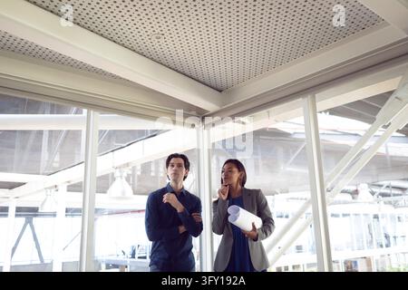 Front view of Caucasian male and female architects interacting with each other in office Stock Photo