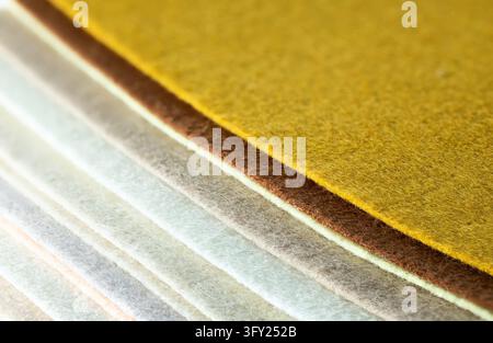 Textured felt sheets overlapping in mustard yellow, brown, cream, and pale gray, creating a tactile abstract textile pattern Stock Photo