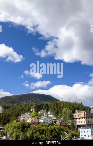 Hillside houses below a forested mountain and blue sky with clouds, Ketchikan, Alaska, USA, May 25, 2026 Stock Photo