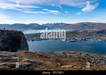 Panoramic view over Tromsø, Norway, with the city, harbor, blue water, rugged mountains and coastal landscape seen from a rocky viewpoint. Stock Photo