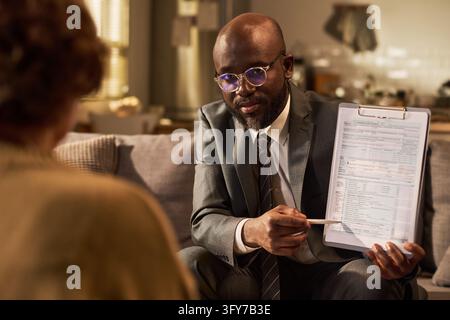 Black Male Financial Advisor Explaining Tax Form on Clipboard to Client Stock Photo