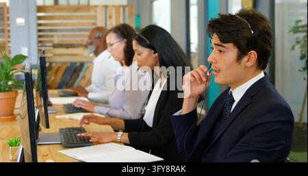 A diverse group of professionals is focused on their work in a modern office environment, with copy space. Each individual appears engaged with their Stock Photo
