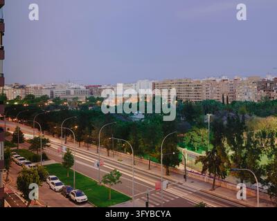 Valencia city street at blue hour with light trails, apartment blocks and the Turia gardens Stock Photo