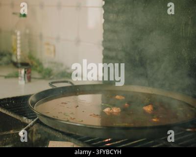 Close-up of a chicken paella with rich broth cooking in a traditional pan Stock Photo