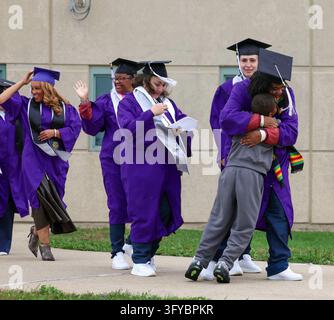 Eighteen women in purple graduation robes and mortarboards toss their ...