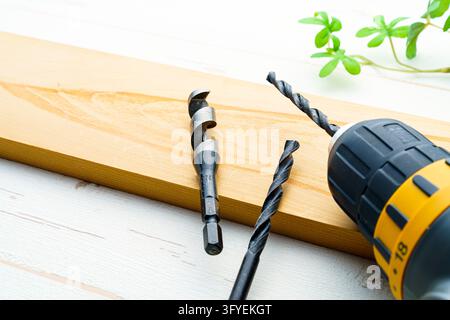 Cordless drill and drill bits beside wooden boards Stock Photo