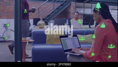 Image of two globes of digital icons spinning over woman using laptop at office. Global networking and business technology concept Stock Photo