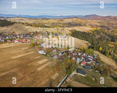 Aerial view of the village of Lom nad Rimavicou nestled in the rolling hills of the Low Tatras, featuring traditional houses and autumn forests, Lom n Stock Photo