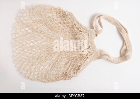 Empty reusable beige cotton string shopping bag isolated on plain minimalist white background Stock Photo