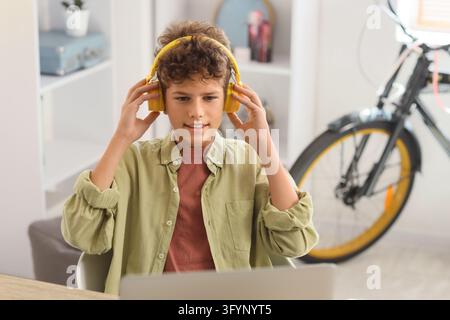 Remote learning and digital education, boy wearing headphones using a laptop for online classes at home in a bright room Stock Photo