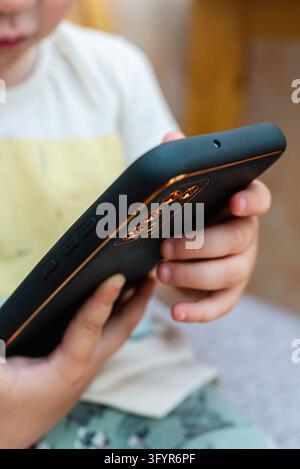 Close-up of child hands holding black smartphone. Stock Photo