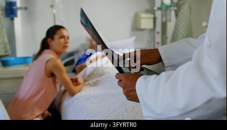 Mid section of male doctor discussing over x-ray report with mother and daughter in the ward art hospital. 4k Stock Photo