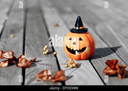 Smiling Halloween pumpkin decoration wearing a black witch hat on weathered wooden boards Stock Photo