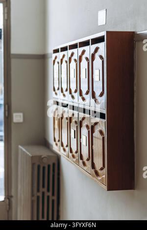 Traditional vintage wooden mailboxes with carved doors mounted on a wall in the entrance hall of a residential building Stock Photo