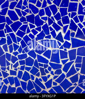 Full frame background of cracked cobalt blue ceramic mosaic tiles embedded in light grey mortar, featuring geometric shapes and irregular abstract pat Stock Photo