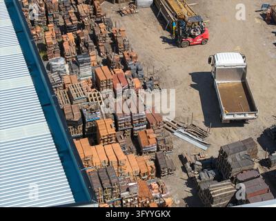 Ferntree Gully, Victoria, Australia - 21 October 2026: Aerial view of stacks of clay roof tiles stored in a construction yard with a forklift and a tr Stock Photo
