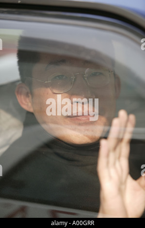 Chinese man waving from a car window Stock Photo