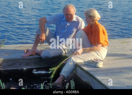 mature couple relaxing on dock by lake in Florida USA Stock Photo