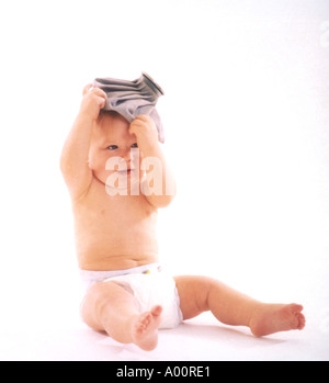 baby boy on floor playing with icepack on head Stock Photo